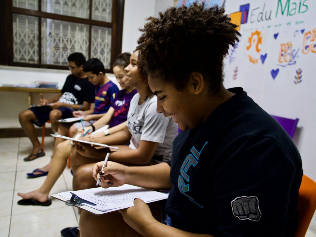 Students in EduMais's Community English program on a line in their chairs smiling in the classroom