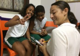 EduMais volunteer English teacher Sally makes the classroom rules with two EduMais students, one making a peace sign