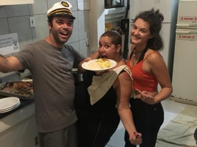 Man and two women with a plate of food in the kitchen