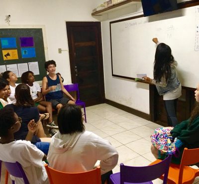 Volunteer English teacher Rebeka points at the whiteboard with the extracurricular English group in the EduMais classroom