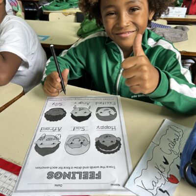 Our methodology Child with a feelings worksheet on the desk. He raises his thumb
