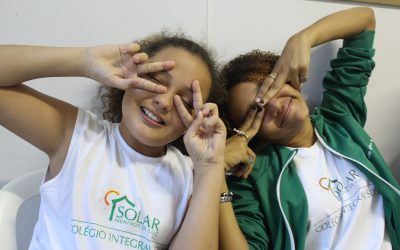 Two of EduMais's girl students make peace signs over their eyes in the classroom