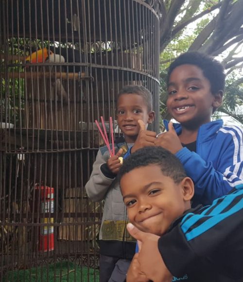 The boys on EduMais's after-school program pose with their thumbs up in front of a toucan on their excursion around Rio's Lagoa