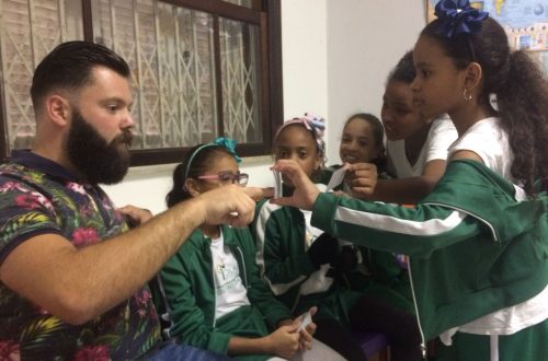 EduMais girl students surround their teacher Daan and get him to point at the answer on a card