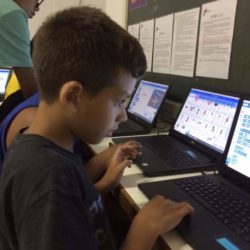 Boys on EduMais's Game Design Camp looking intently at their computers