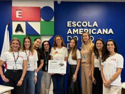 EduMais team receiving a donation from the Parent Teacher Association at the American School in Rio de Janeiro, supporting free education programs for favela youth.