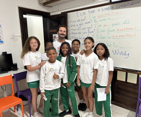 Volunteer teacher with students in front with English lesson on the white board