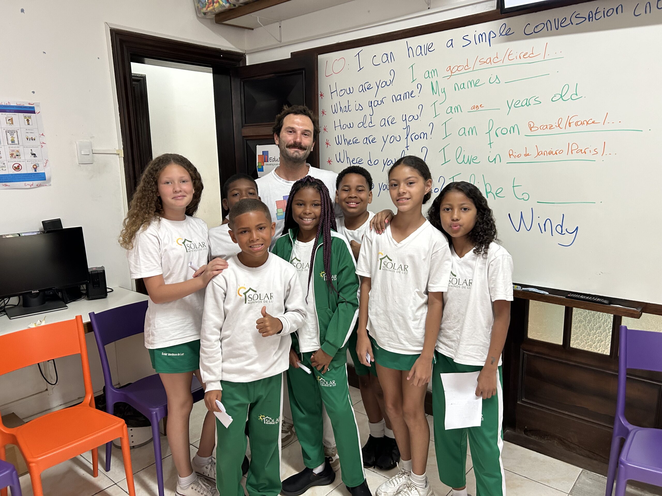 Volunteer teacher with students in front with English lesson on the white board