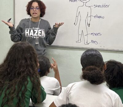 woman in front of classroom with body parts on the board