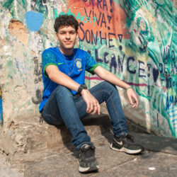 Samuel Alves Young man sitting in front of Graffiti.