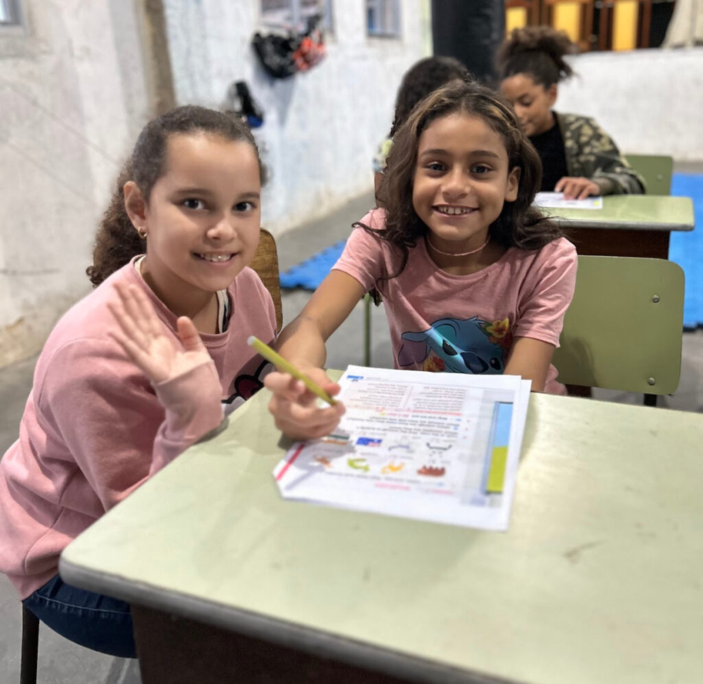 Twee lachende meisjes werken aan een werkblad tijdens een les van EduMais